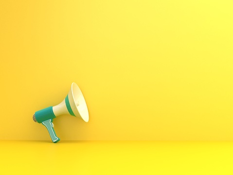 Blue megaphone on yellow background. Copy space for announcement concepts.