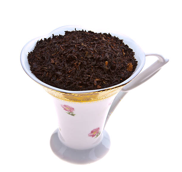 Cup of dry black tea leaves stock photo