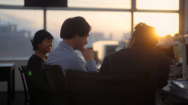 Group of multi-ethnic business people talking casually in office during sunset