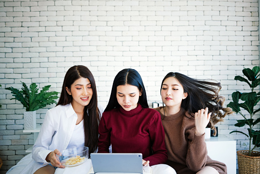 Cheerful young women watching movie on laptop in the bedroom