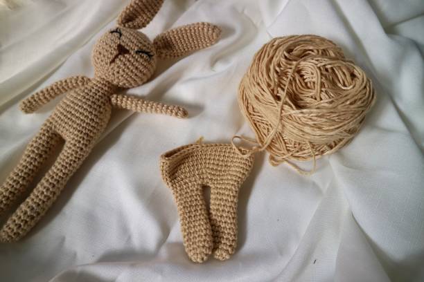 istock Crocheted rabbit on the white cloth background. Knitted toy, handmade, needlework, bunny amigurumi. 1492184402