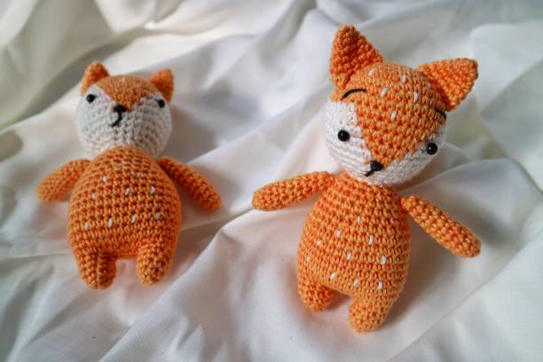 istock Orange wolf crochet handmade doll made from yarn. Stuffed toy on fluffy background. 1492185470