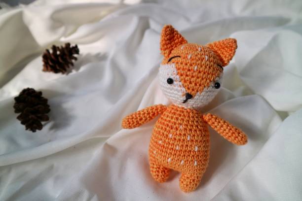 istock Orange wolf crochet handmade doll made from yarn. Stuffed toy on fluffy background. 1492185494