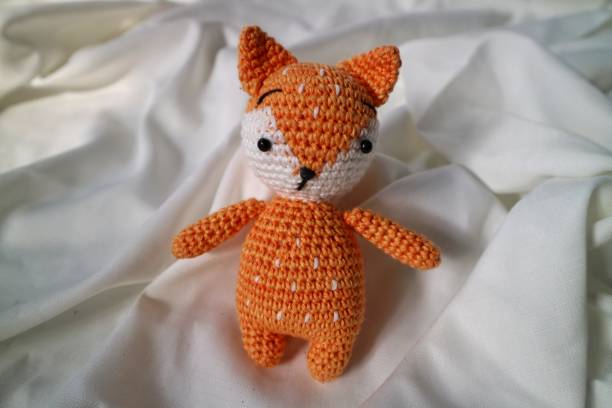 istock Orange wolf crochet handmade doll made from yarn. Stuffed toy on fluffy background. 1492185518