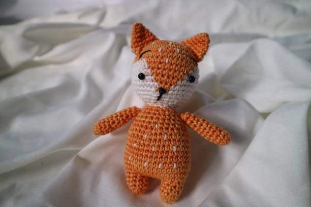 istock Orange wolf crochet handmade doll made from yarn. Stuffed toy on fluffy background. 1492185535