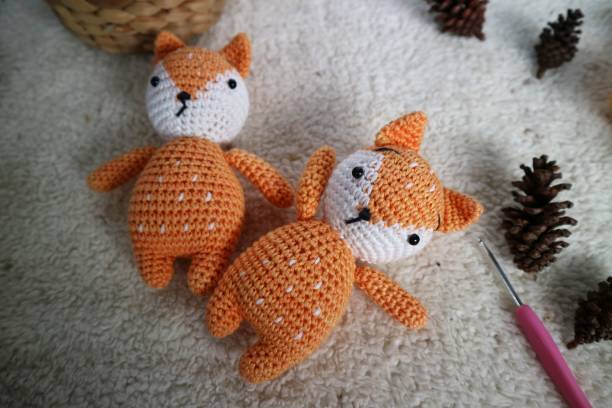 Orange wolf crochet handmade doll made from yarn. Stuffed toy on fluffy background.