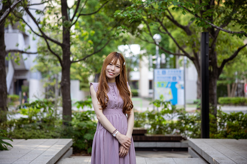 Portrait of young female influencer in public park in city - smiling