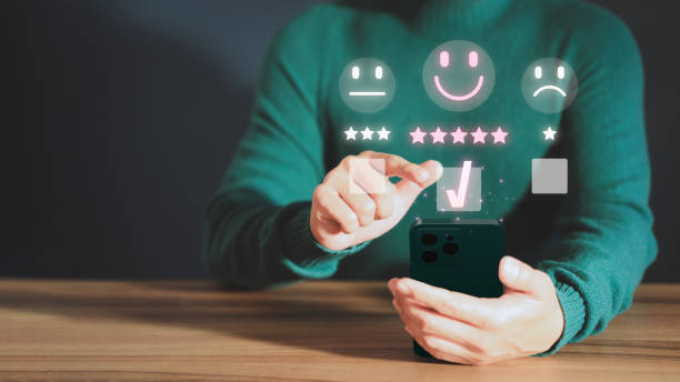 istock Customer service experience assessment and business satisfaction survey. Man hand using a mobile phone with popup smile face icon for feedback review satisfaction service opinion and testimonial. 1492192415
