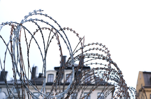 Close-up of barbed wire on the walls of a building against the sky.