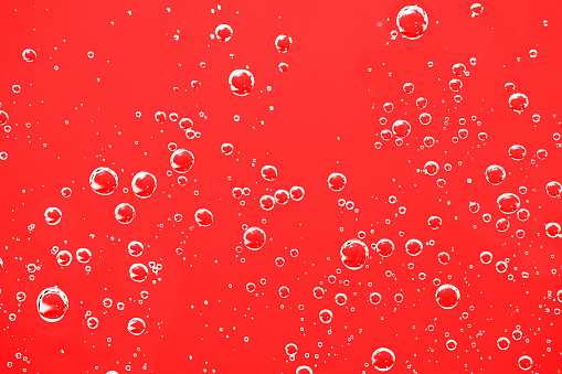 Water bubbles background. Macro oxygen bubbles in water over red background.