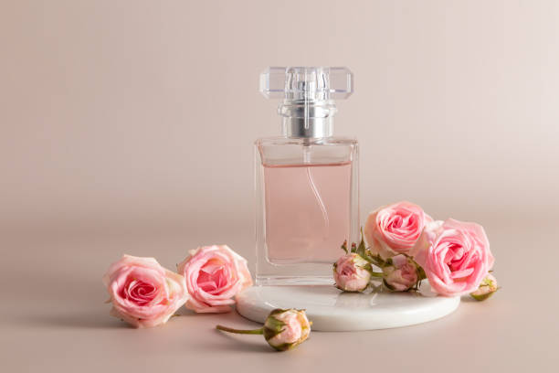 istock Beautiful cosmetic perfume bottle on a white round catwalk with small pink roses. front view. Blank bottle layout. Product advertising. 1492198625