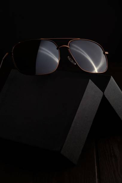 Brown Sunglass on the black case with dark background Aviator sunglasses are a classic style that have been popular for decades. They are characterized by their large, teardrop-shaped lenses and metal frames. Aviator sunglasses are a great choice for people with all face shapes and can be worn for a variety of occasions. luxury eyewear stock pictures, royalty-free photos & images