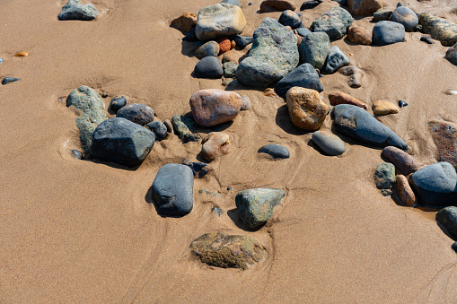 A sandy beach with tidal grass growth, dead wood, stones and a inukshuk