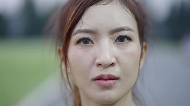 Asian woman face drenched in sweat after exercise.