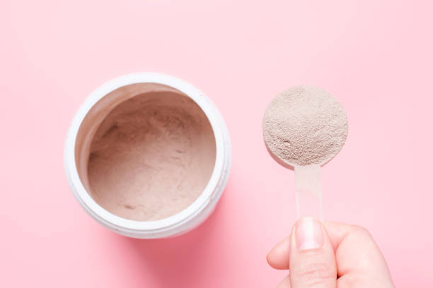 istock Chocolate protein powder in scoop and plastic jar on pink background. 1492205746
