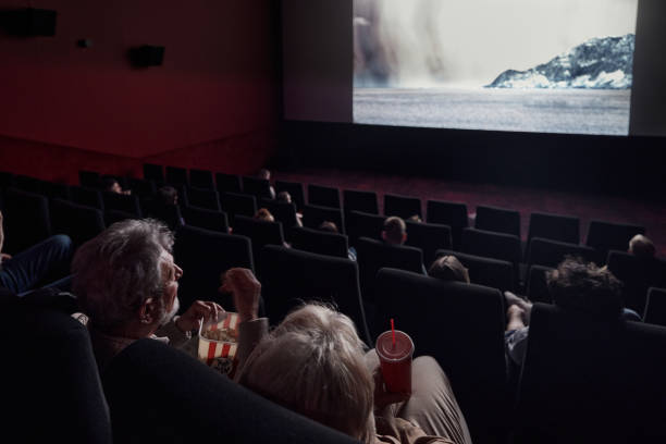 Movie projection in cinema! Back view of a mature couple watching a movie in cinema. film premiere stock pictures, royalty-free photos & images