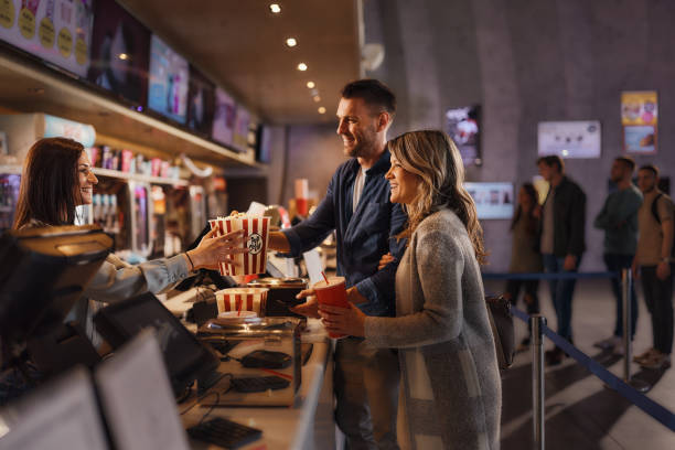 Happy couple buying popcorn and drinks in cinema. stock photo