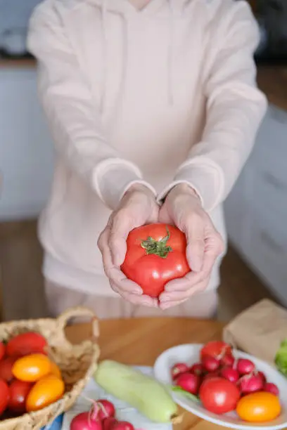 Photo of Age woman holding a large ripe tomato in her hands