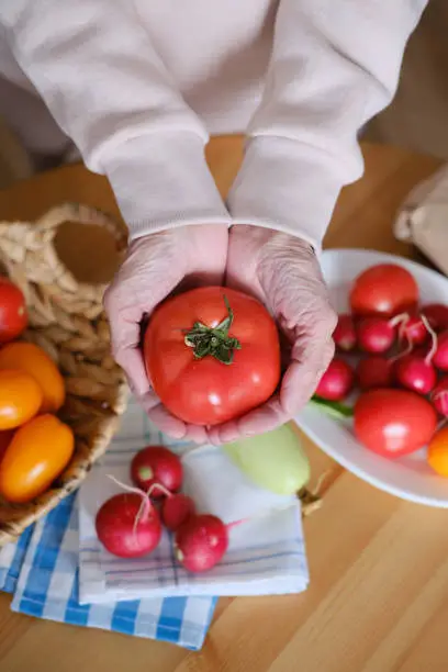 Photo of Age woman holding a large ripe tomato in her hands