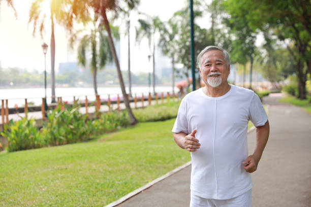 istock Happy and smiling asian senior man doing exercise and jogging or walking with relaxation for healthy in park outdoor after retirement during summer time. Health care elderly outdoor lifestyle concept. 1492208820