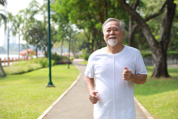 istock Happy and smiling asian senior man doing exercise and jogging or walking with relaxation for healthy in park outdoor after retirement during summer time. Health care elderly outdoor lifestyle concept. 1492208821