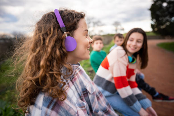 Group of teenagers talking while sitting in park stock photo