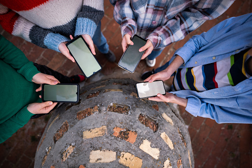 High angle view of group of teenage children standing in the circle and using mobile phones