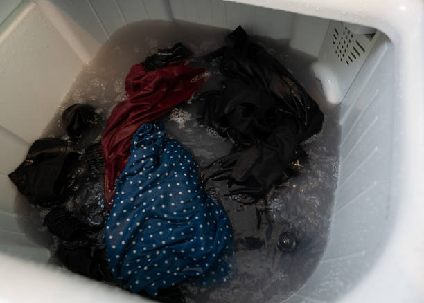 istock Dirty clothes in top loading washing machine. Clothes with bubble of laundry detergent in washing machine. Laundry concept. Top load washer. Housework. Washing machine and dirty water from cleaning. 1492211219