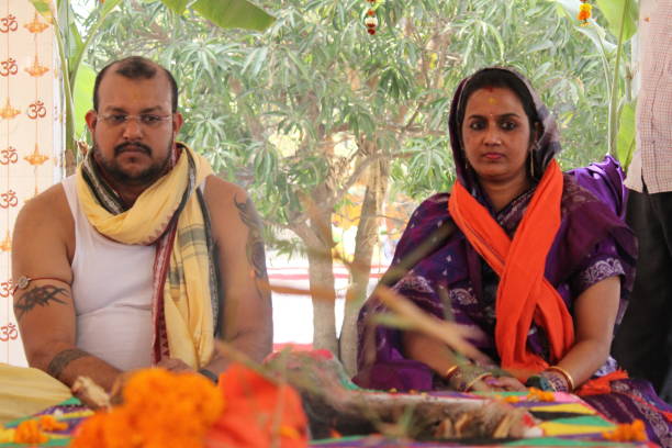 Bratopanayan in progress in an Odia household. During the upanayana ceremony, the young initiate receives the yajnopavita, or sacred thread, which he wears across his chest from the left shoulder to the waist. Bratopanayan in progress in an Odia household. During the upanayana ceremony, the young initiate receives the yajnopavita, or sacred thread, which he wears across his chest from the left shoulder to the waist. india indigenous culture indian culture women stock pictures, royalty-free photos & images