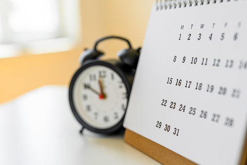 Part of analogue plain wall clock on white wall background. Four o'clock twelve minutes. Close up with copy space, timing, time management, opening hours time, school concept and lunch time