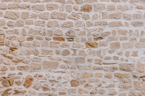 Outdoor unevenly shaped stone wall with binding material, smooth texture, full frame, backgrounds