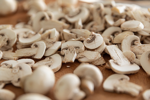 Champignon white button mushrooms chopped on wooden cutting board