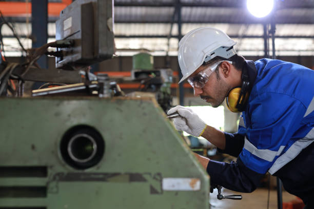 istock Technician engineer or worker man in protective uniform with safety hardhat maintenance operation or checking lathe metal machine at heavy industry manufacturing factory. Metalworking concept 1492223023