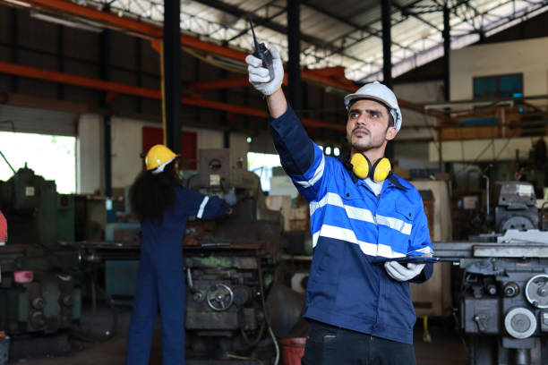 istock Technician engineer man in protective suit stand and use walkie talkie radio and tablet while controll or maintenance operation work lathe metal machine at heavy industry manufacturing factory 1492223041