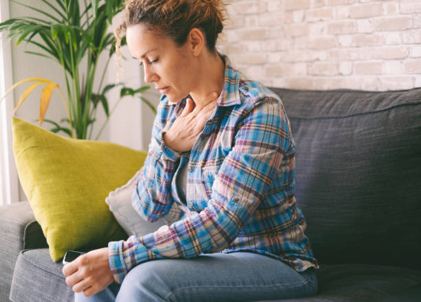 istock One woman alone at home touching her chest for suffering panic attack and anxiety problems. People with bad mental health and depression mind state. Female sitting on sofa at home stressed and tired 1492226880