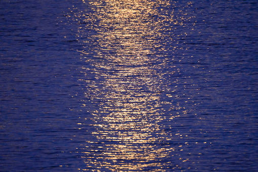 Texture blue water with ripples and reflections of golden light, canbe used as natural background