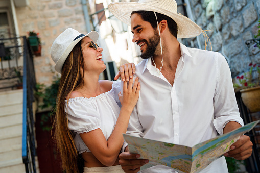 Happy young couple of travellers holding map in hands and enjoying summer vacation