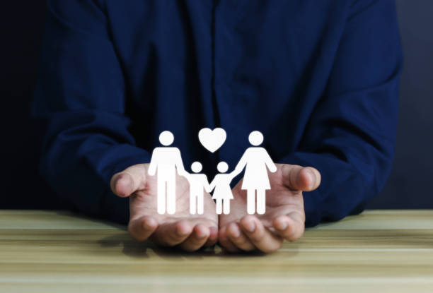 istock Hands protect family on wooden table. 1492238437