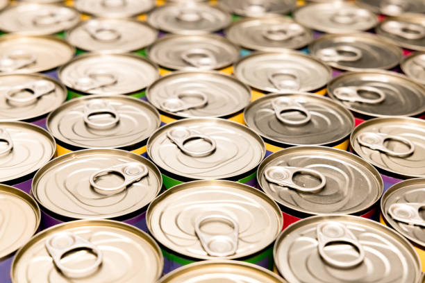 Open empty tin cans from under a canned food, different sizes with various white and yellow covering on a gray background