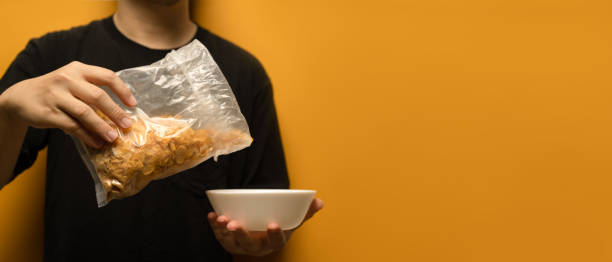 istock Man pouring cereals into a white bowl isolated on yellow background 1492240543