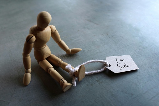 Selective focus image of doll with tag FOR SALE. Human trafficking concept