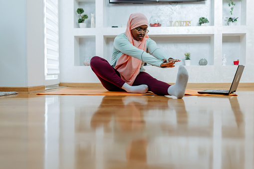 Experience the energy and determination of a young Muslim woman as she takes her workout routine to the living room floor