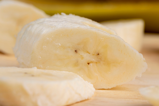 a ripe sweet banana cut into pieces lies on the table , ripe yellow bananas on a wooden board