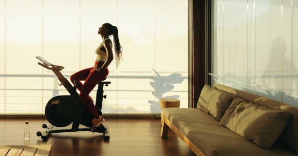 istock Female athlete using exercise bike in home workout routine 1492255653