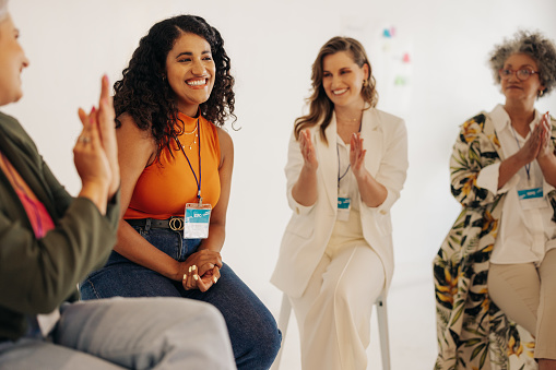 Happy businesswomen applauding their team mate during a conference meeting in a modern workplace. Group of successful businesswomen working together in an all-female startup.