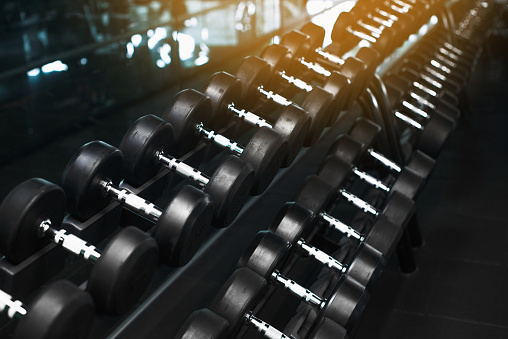 Black dumbbell set. Close up many metal dumbbells on rack in sport fitness center , Weight Training Equipment concept. Rows of dumbbells