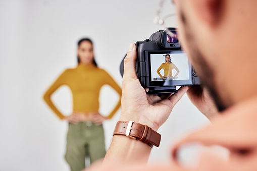 Camera, photography and photographer with woman fashion model in studio for creative, advertising and image. Media, backstage and professional man with girl and equipment for photoshoot capture