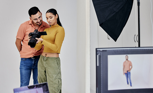 Teamwork, photographer and startup people with camera in studio set for shoot, magazine project or online content. Planning, focus or girl examine picture for digital catalog or fashion web design