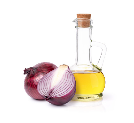 Onion oil in glass bottle and fresh red onion isolated on white background.