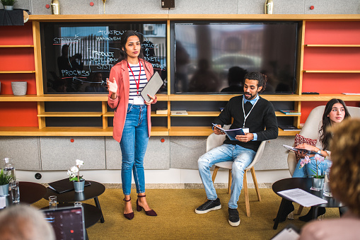 Asian Businesswoman Presenting Data At A Meeting In A Modern Office Using Digital Tablet